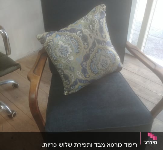 כרית מעוצבת על כורסה מרופדת בבד כהה